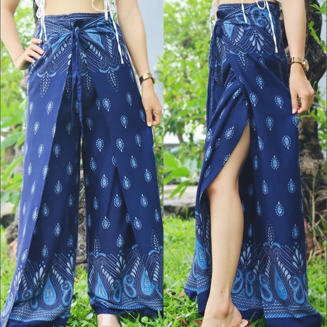 A person wearing boho blue wrap pants with intricate white patterns, paired with a white tied-up top, showcasing the front and side views of the outfit.