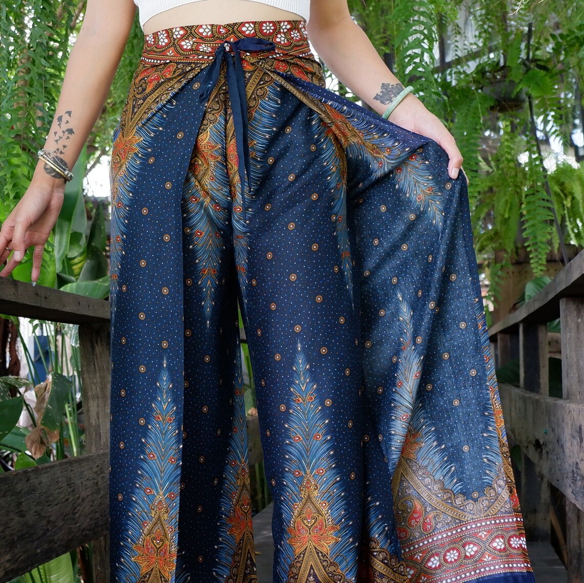 Elegant boho feather print wrap pants in a natural outdoor setting.