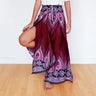 Model lifting leg in burgundy feather print boho wrap pants with tribal floral borders.