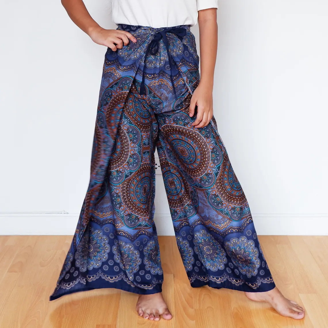 Woman posing in boho mandala wrap pants in rich midnight indigo and copper tones.