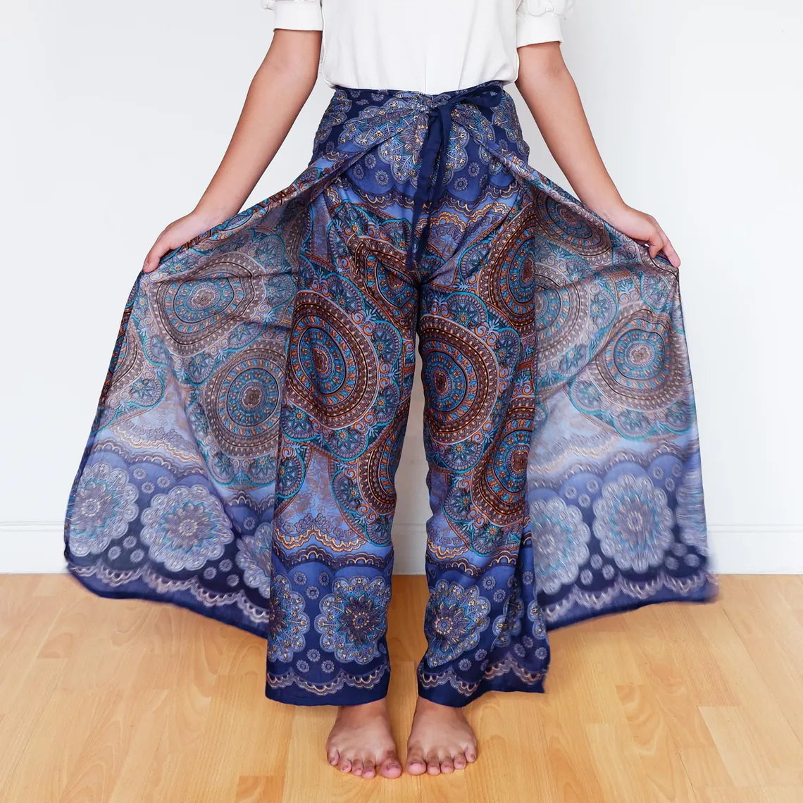 Model showing wide flowing midnight indigo wrap pants with circular mandala patterns.