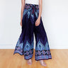 Woman in navy blue boho wrap pants with flowing feather print and decorative borders.