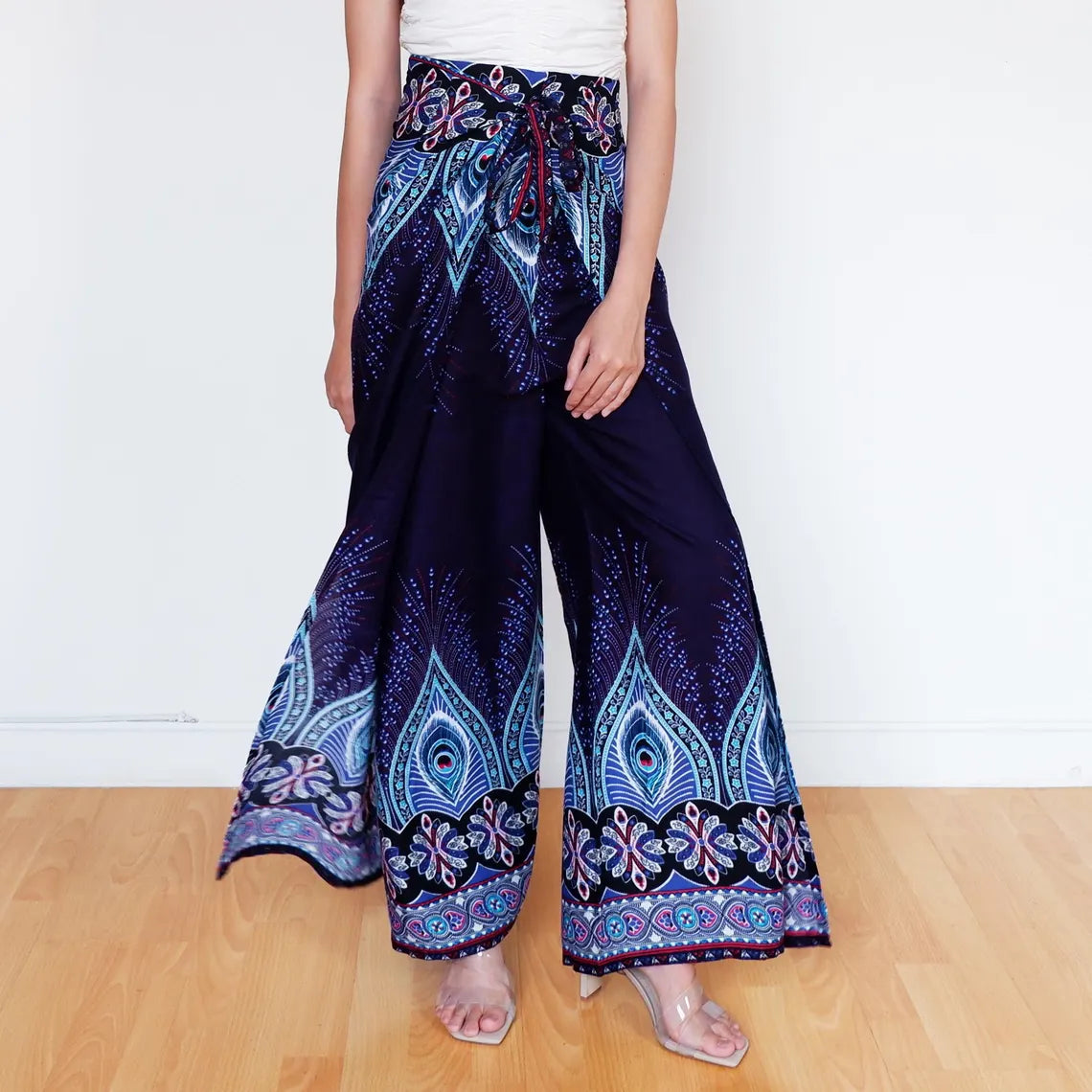 Woman in navy blue boho wrap pants with flowing feather print and decorative borders.