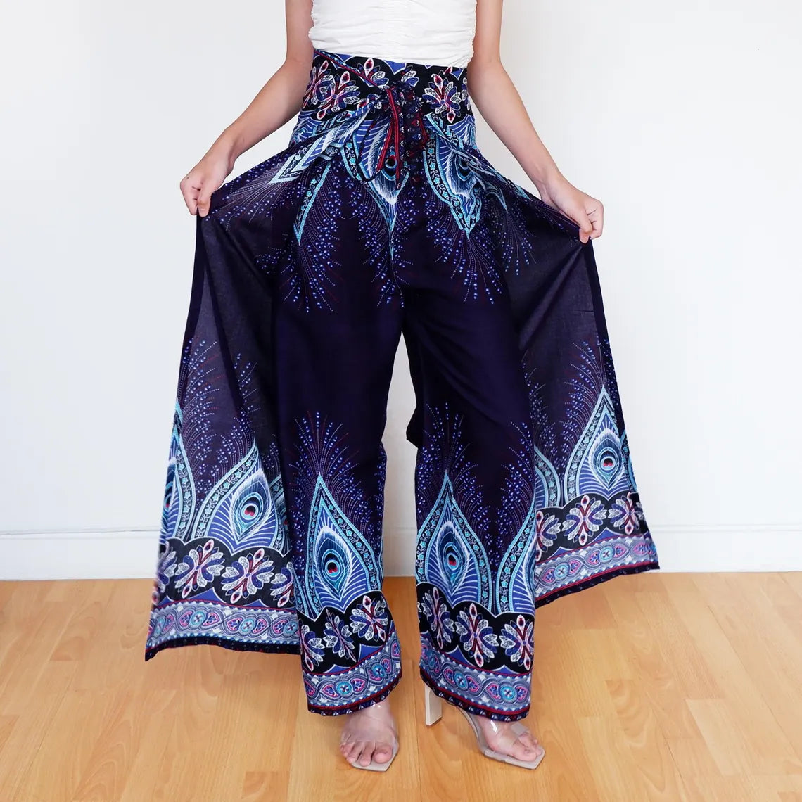 Model showing wide-leg navy boho wrap pants with blue feather and floral detailing.