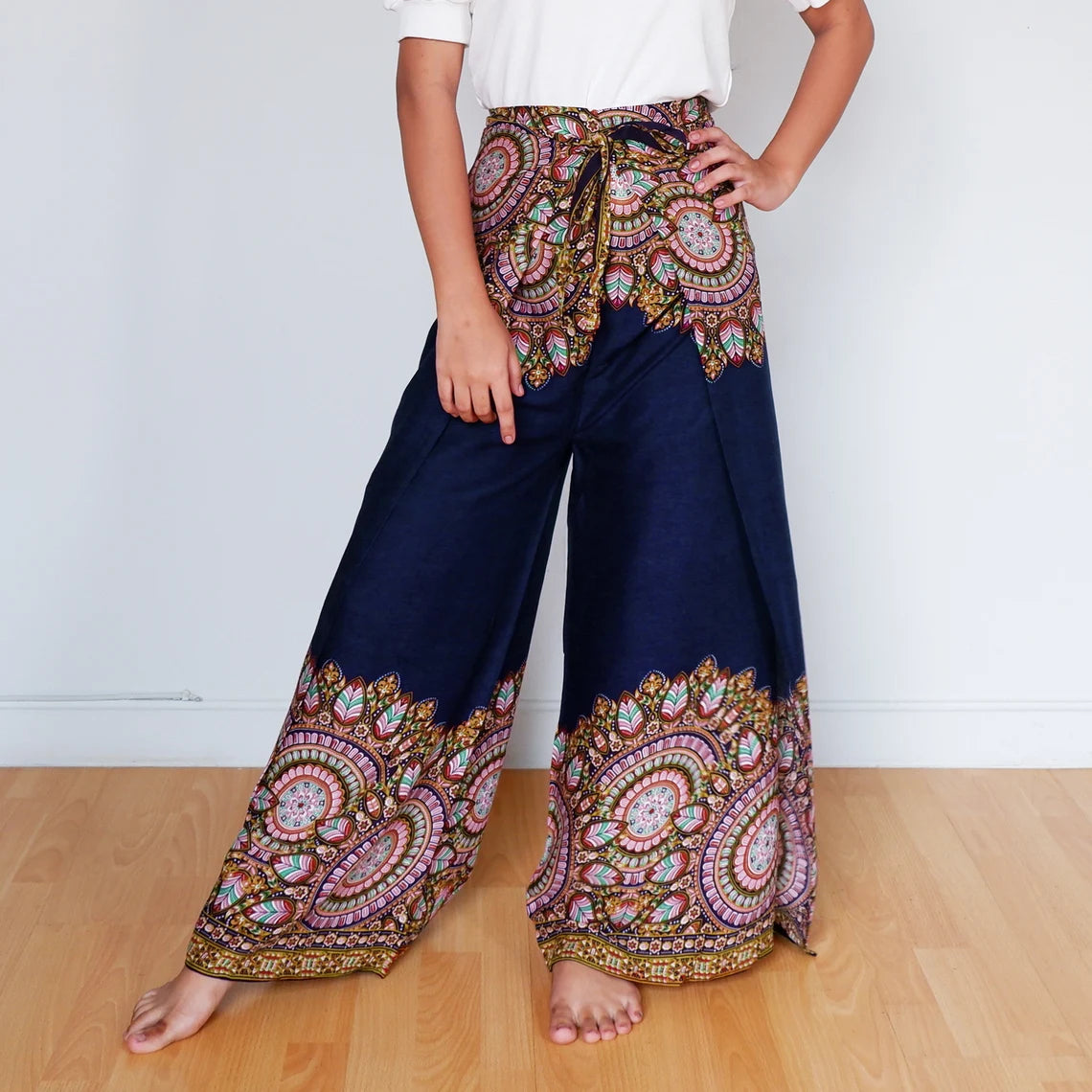 Woman posing in navy wrap pants with pink and gold mandala border design.