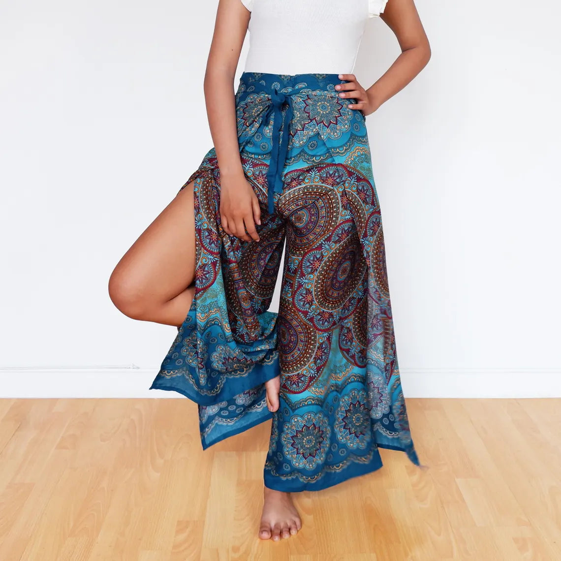 Model lifting leg in flowy blue mandala wrap pants, perfect for beach or festival wear.