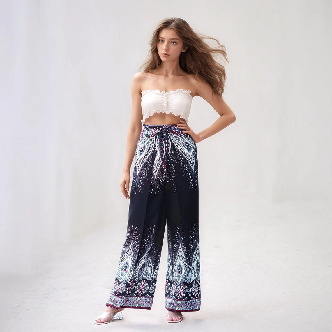 Model posing in navy boho wrap pants with white peacock feather design, perfect for a beach or festival look.