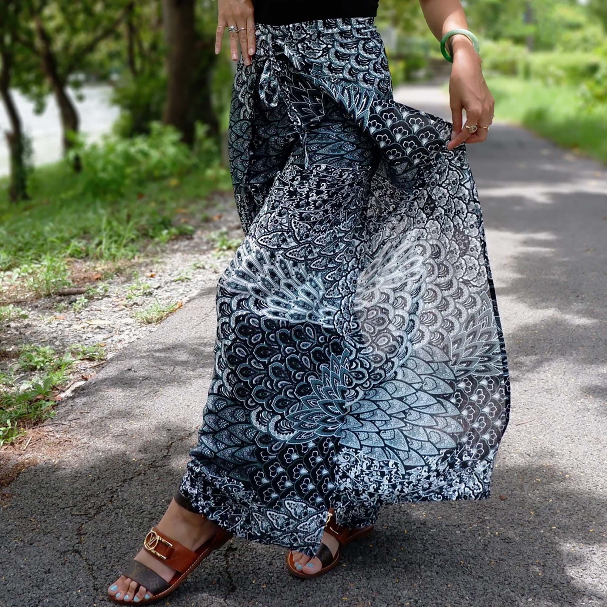 Graceful white boho wrap pants featuring Aegean teal petal prints, paired with elegant sandals for a sophisticated look.