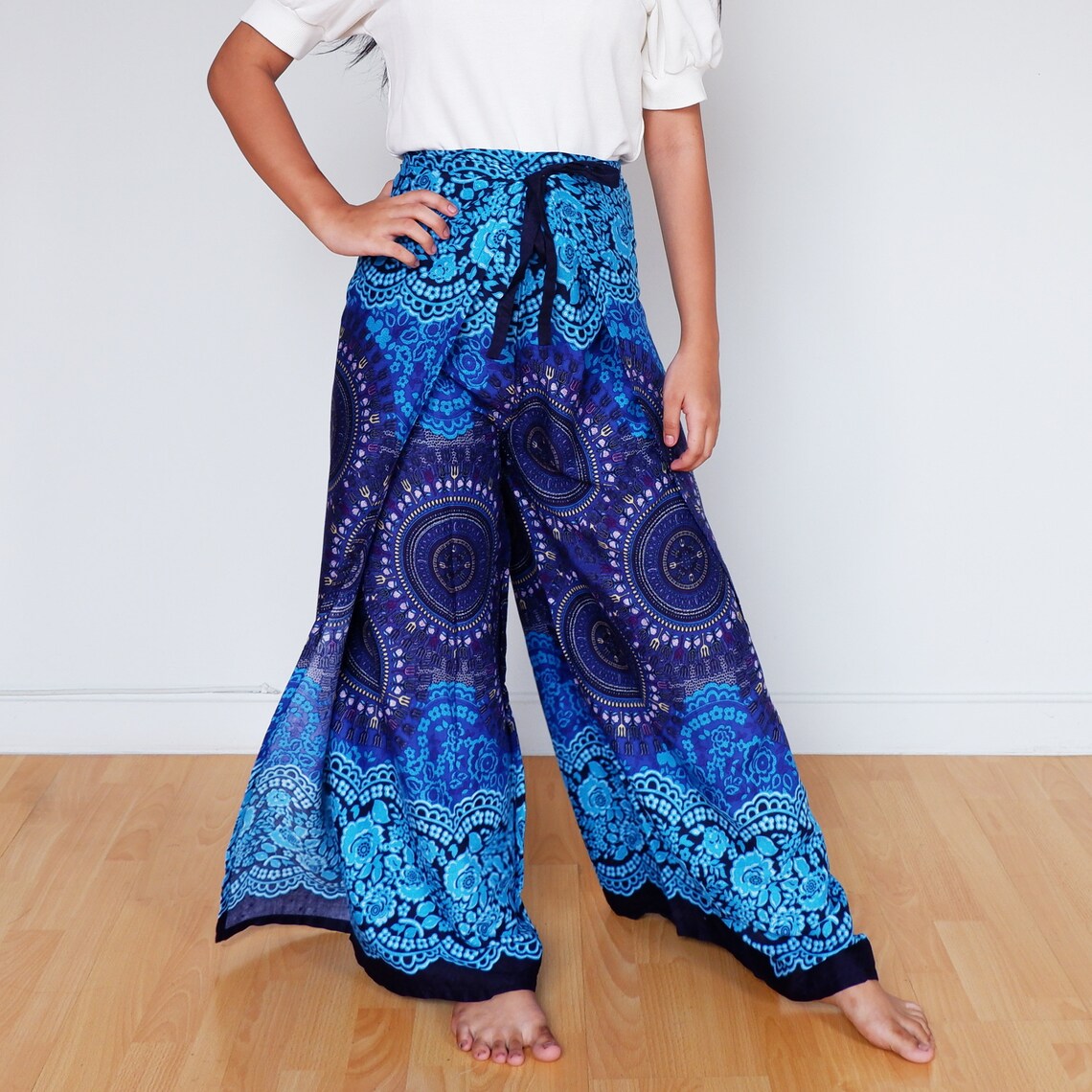 Model wearing boho wrap pants in blue and navy with mandala and floral patterns, barefoot indoors
