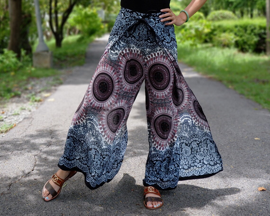 Light mauve and gray festival wrap pants with circular mandala pattern, styled with sandals on a trail
