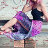Closeup of wrap pants with pink and purple mandala design, model sitting on bench
