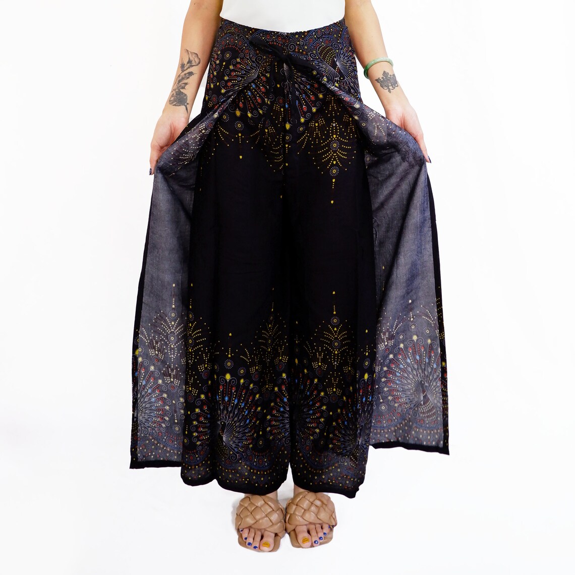 Trendy black boho wrap pants with a distinctive peacock feather print, perfect for a fashionable and comfortable look.