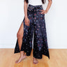 Black wrap pants with bold peacock feather print and leg slit, boho festival vibe
