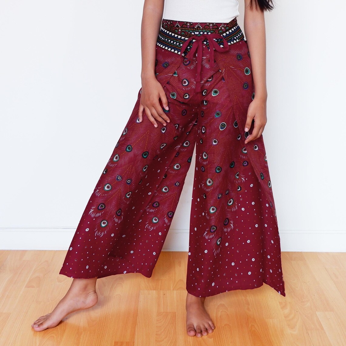 Maroon wrap pants with tribal peacock feather print, styled in relaxed boho fit
