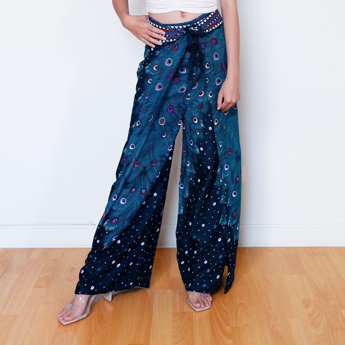 Handmade navy blue wrap pants with peacock print, modeled with angled leg pose
