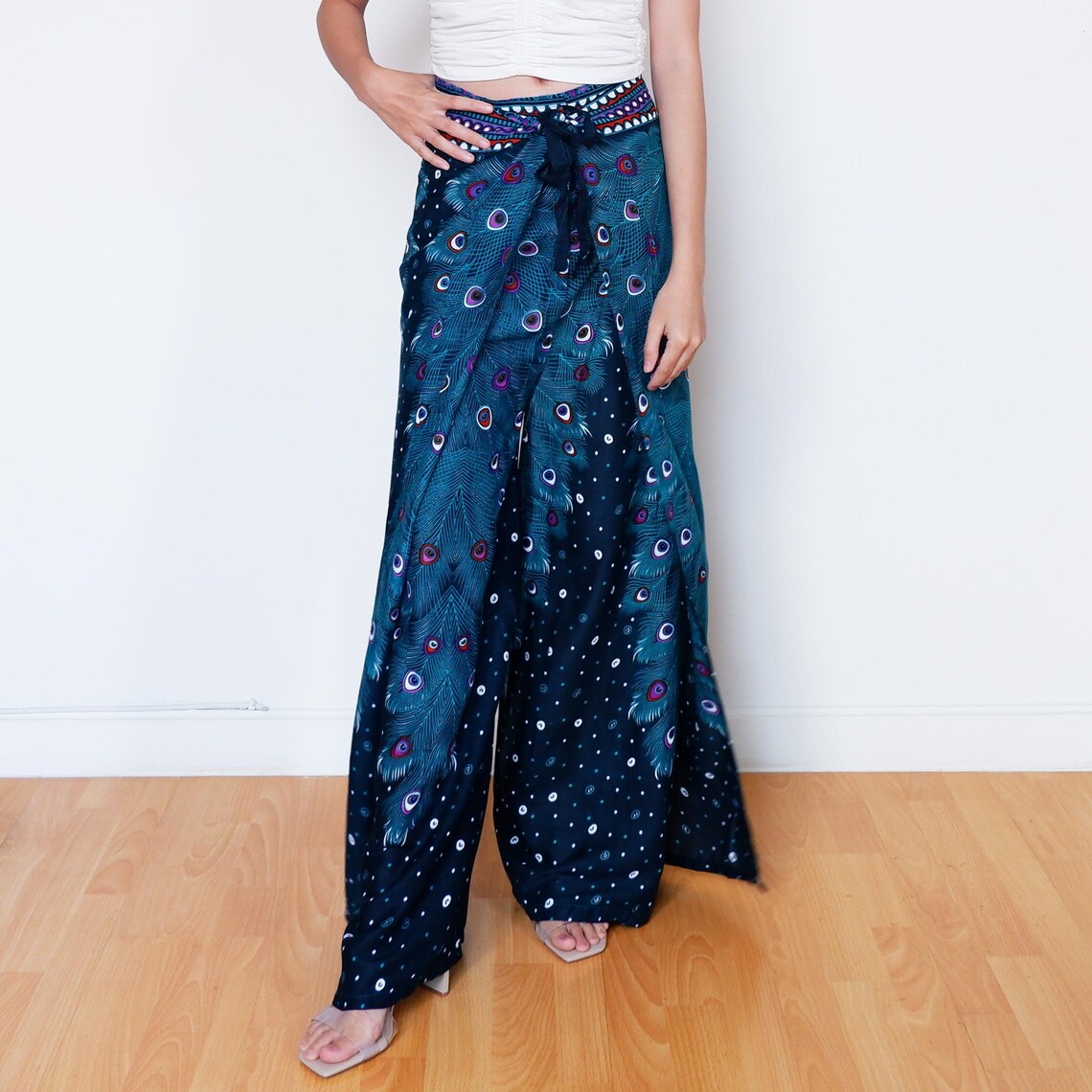Boho navy blue wrap pants with handmade peacock design, model standing with hand on waist
